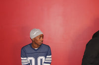 Alamòd Archives Orijin Grey Skull Cap shown on a model, featuring a stylish, fitted grey skull cap with branding details.